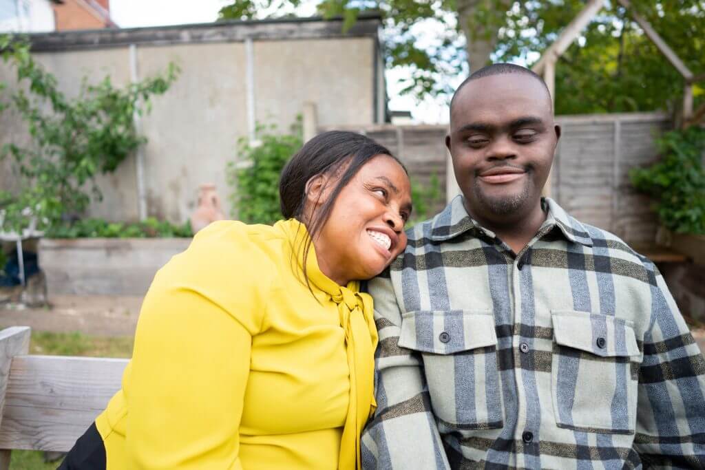 Mother and adult son with Down syndrome sitting on bench in garden