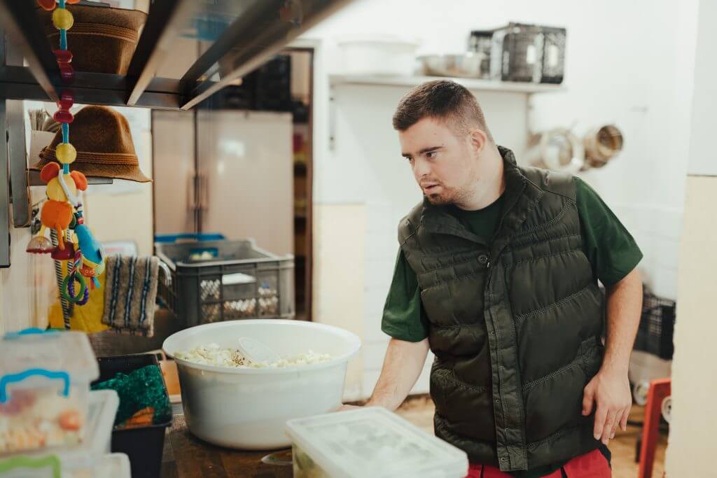Man with down syndrome working in kitchen, preparing food for animals